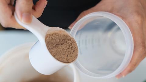 Femme versant de la poudre de protéine dans une tasse