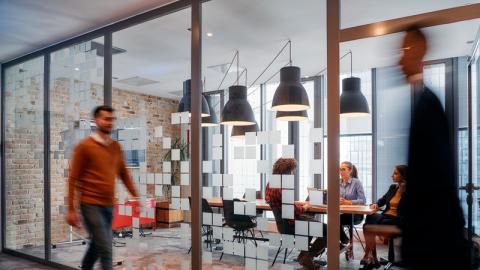 A group of business professionals walk down the corridor next to their office