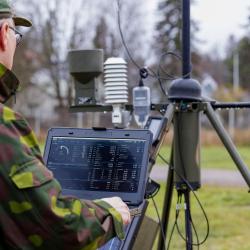 Military worker on laptop with TacMet Tactical Meteorological Observation System.